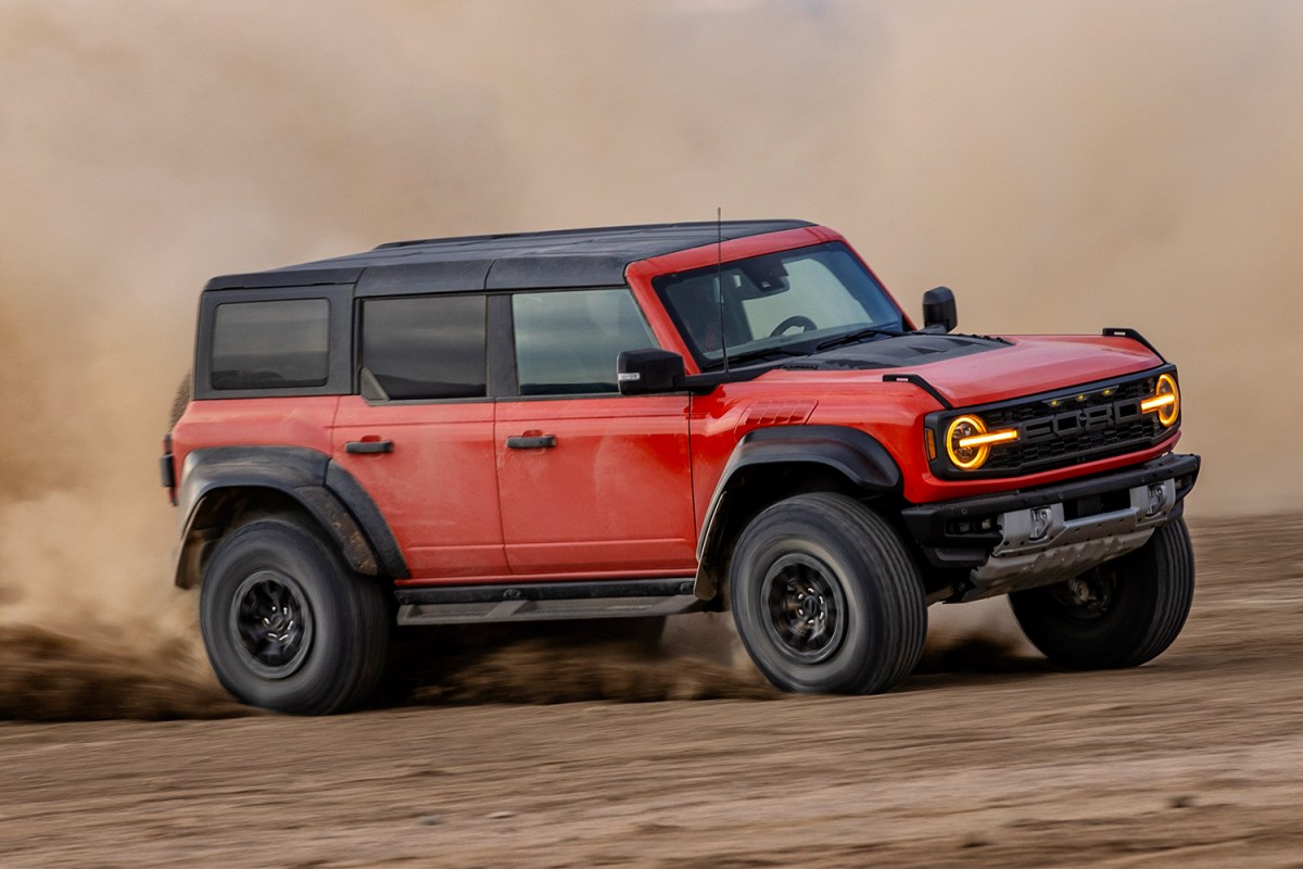 A red Ford Bronco Raptor churning up dust and dirt in the desert. We reviewed the rock-crawling, desert-racing version of Ford's popular Bronco SUV.