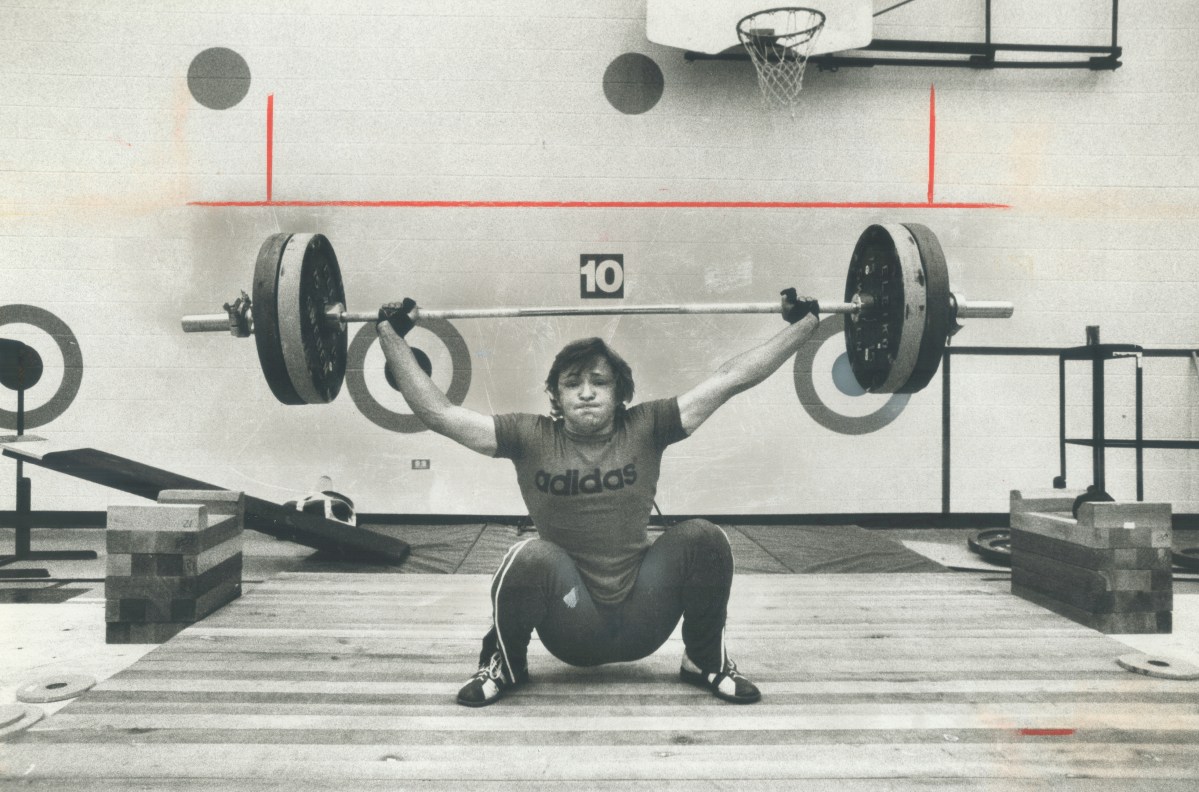 A vintage photo of a lifter struggling to lift a bar.