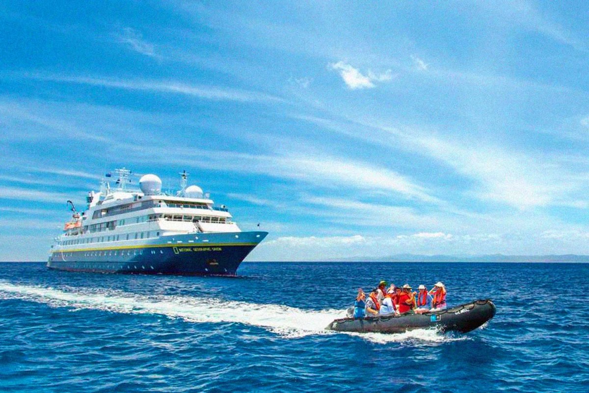 a smaller boat full of passengers sailing away from a cruise ship