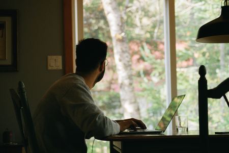 A man at a desk staring out a window.