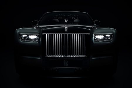 The grille of the Rolls-Royce Phantom Series II, shown in the dark with a lit up grille and headlights