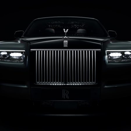 The grille of the Rolls-Royce Phantom Series II, shown in the dark with a lit up grille and headlights