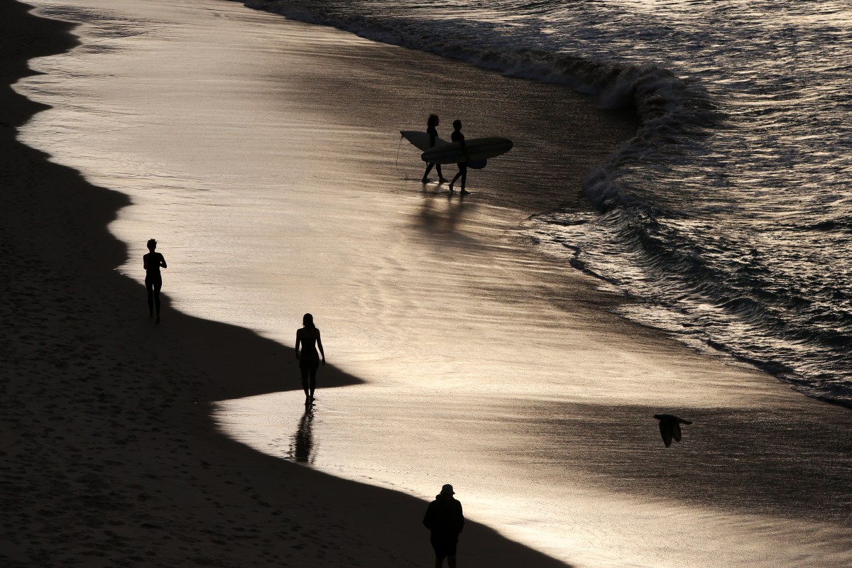 A sepia-tinted photo of people walking down a beach.