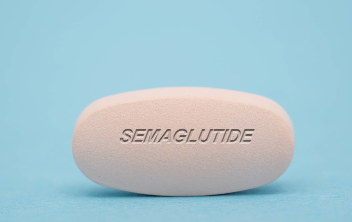 A large semaglutide pill against a blue background.
