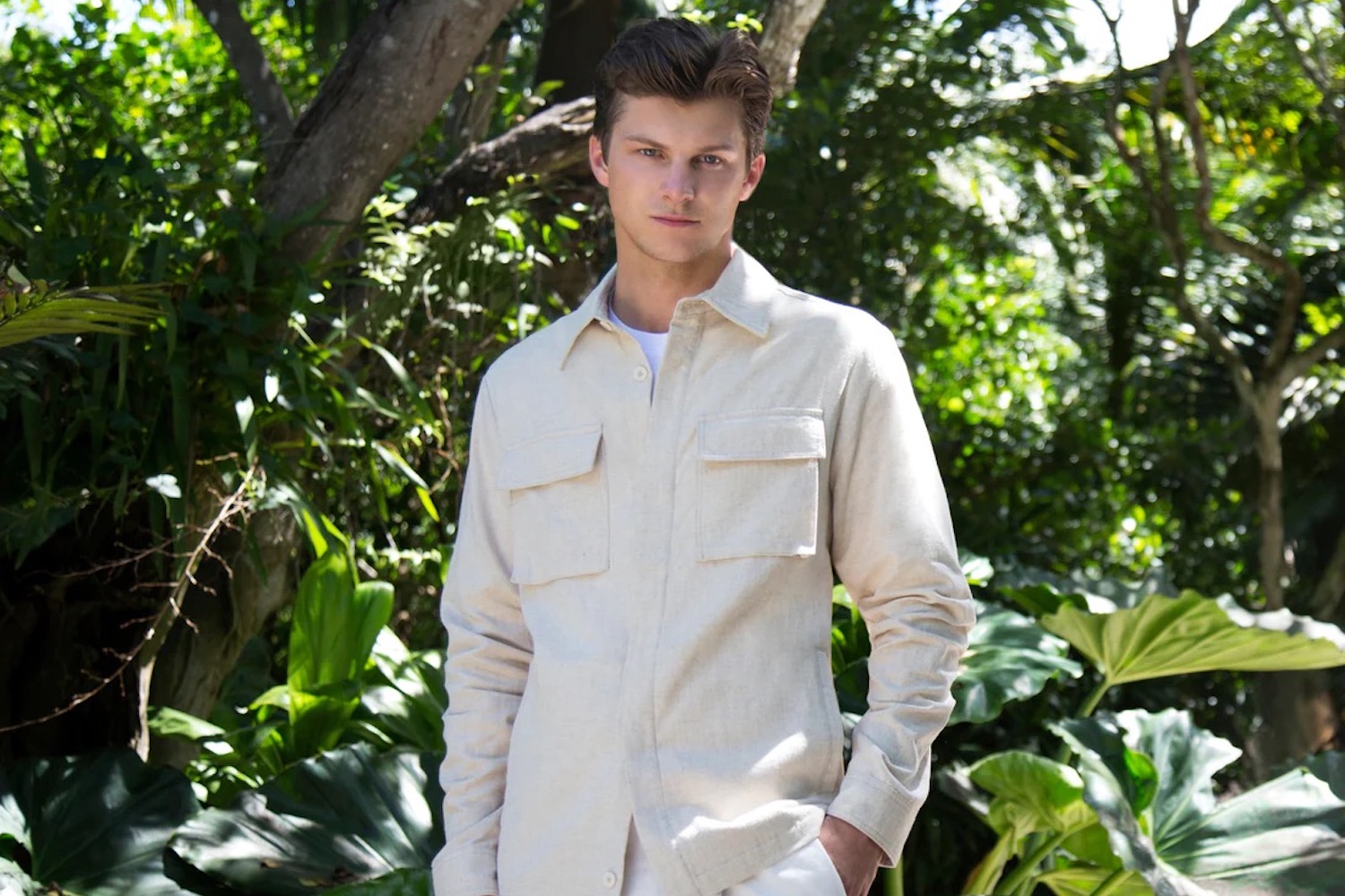 a model in a white Bugatchi overshirt against a leafy background