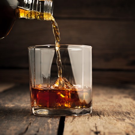 close-up of pouring dark rum on the rocks