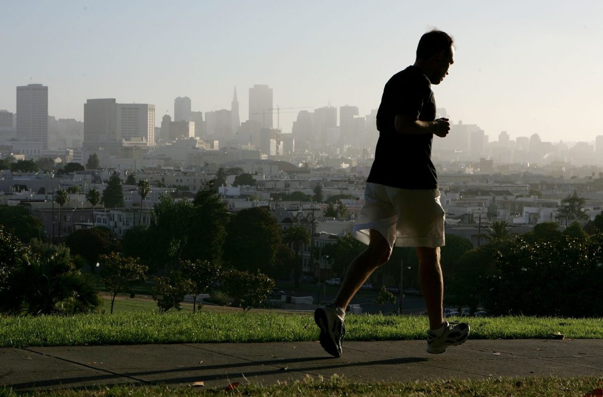 With the San Francisco skyline in the background, a jogger runs through Dolores Park