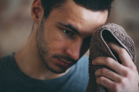 Man wiping sweat off his face with a towel.