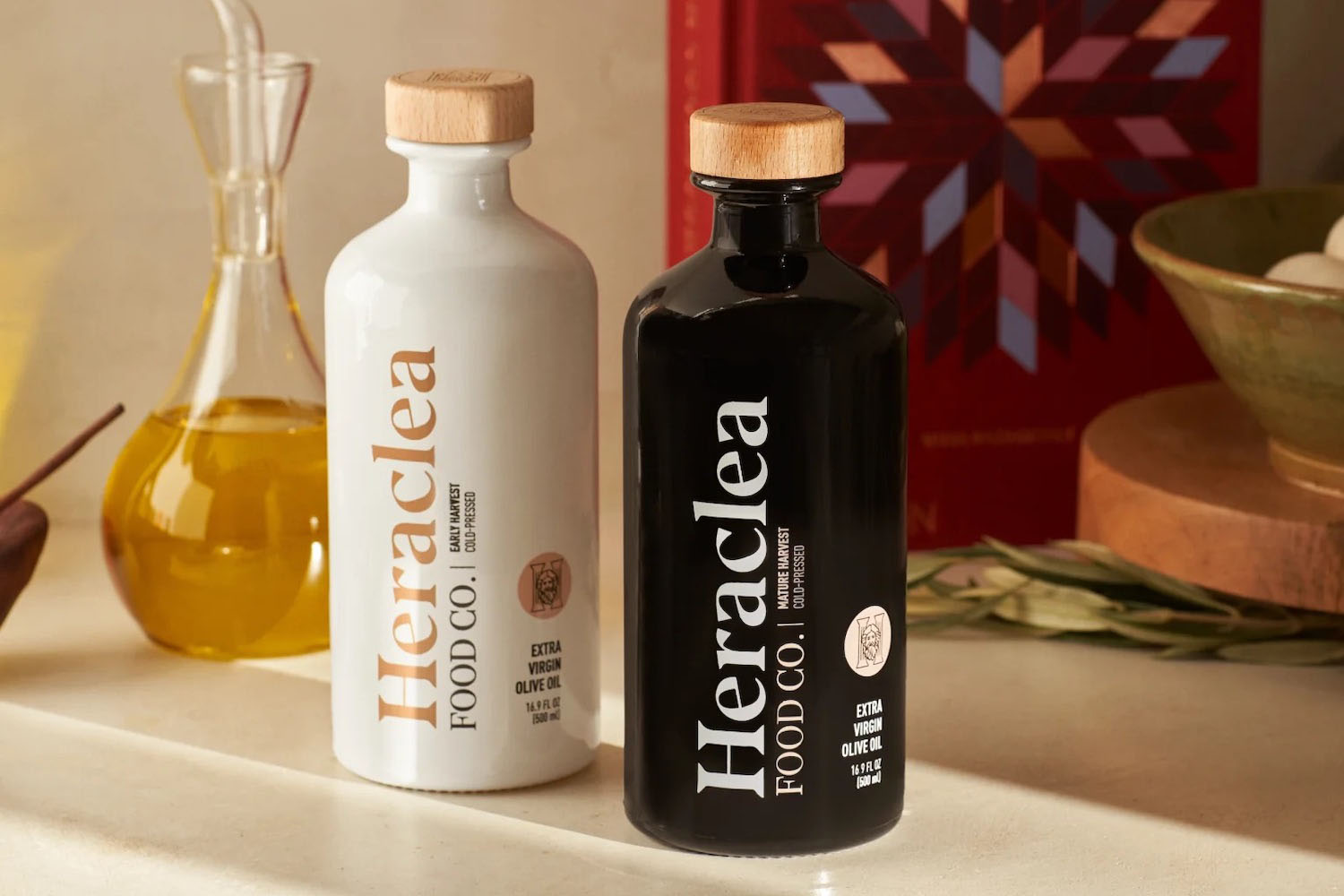 two bottles of Heraclea Olive Oil on a marble tabletop