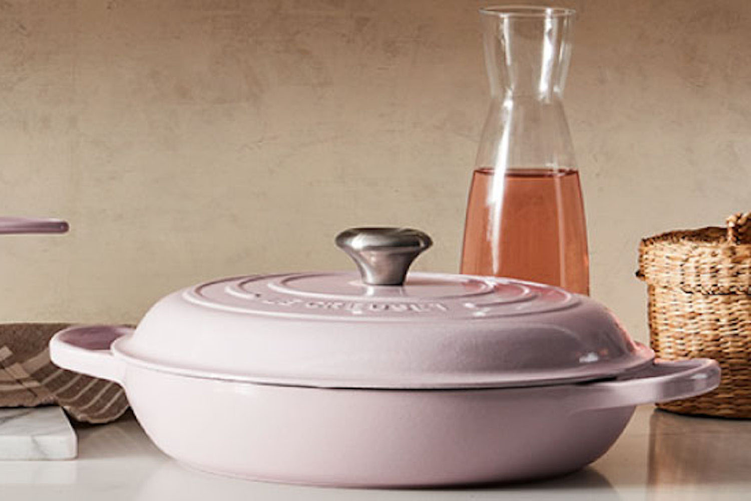 a pink-colored Le Crueset Dutch Ocen on a marble table
