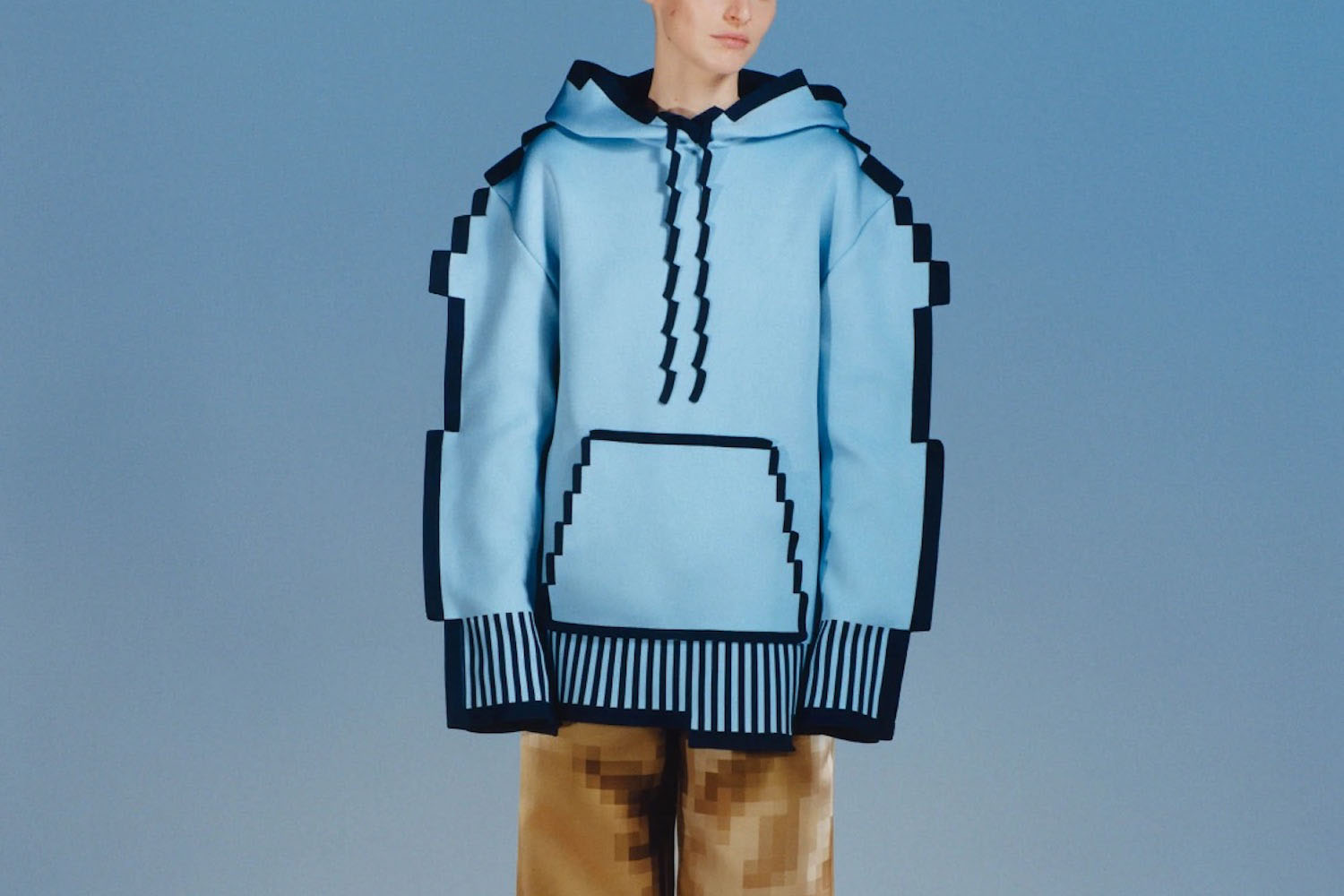 a model in a blue Loewe Pixelated Hoodie on a sky blue background