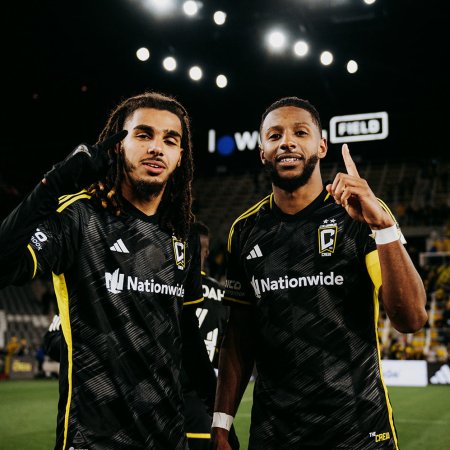 Mohamed Farsi and Steven Moreira of the Columbus Crew soccer club in MLS pose for a picture, their index fingers pointing up, on the pitch at their home stadium, Lower.com Field