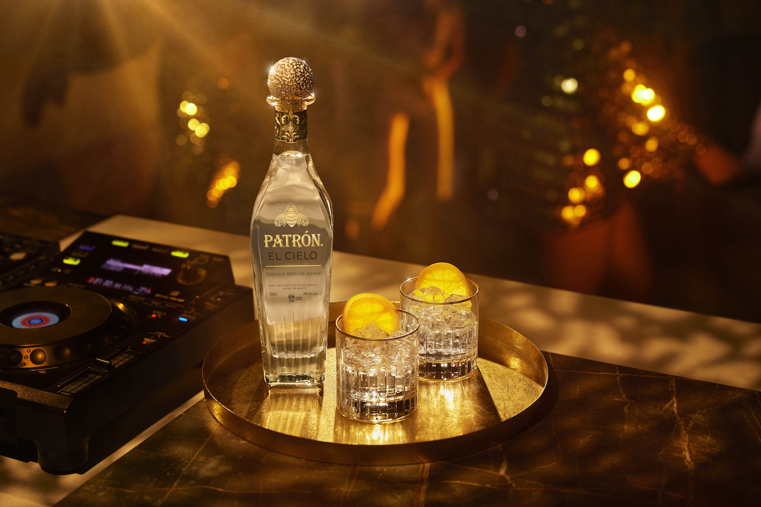 a bottle of Patrón El Cielo Tequilla on a silver tray in a dark room