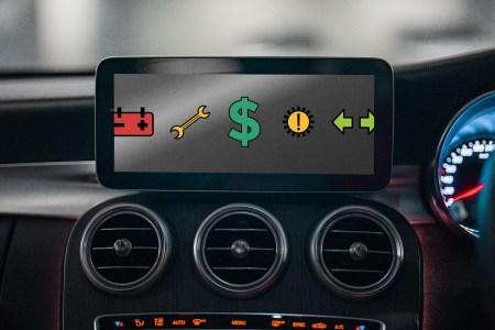 A screen on a car dashboard showing warning icons and a dollar sign. We discuss the problem with modern advanced car-safety systems.