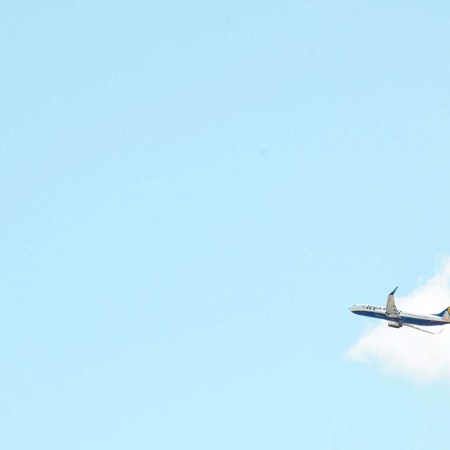 An airplane taking off with a blue sky and clouds behind it
