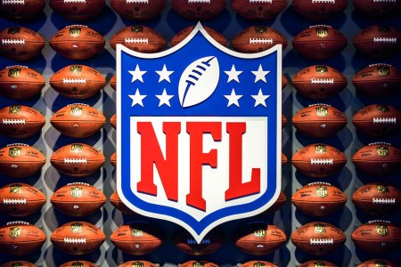 The NFL crest hovers in front of rows of footballs