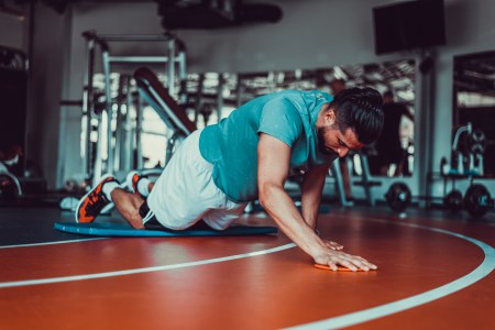 A man doing push-ups with his knees on the floor.