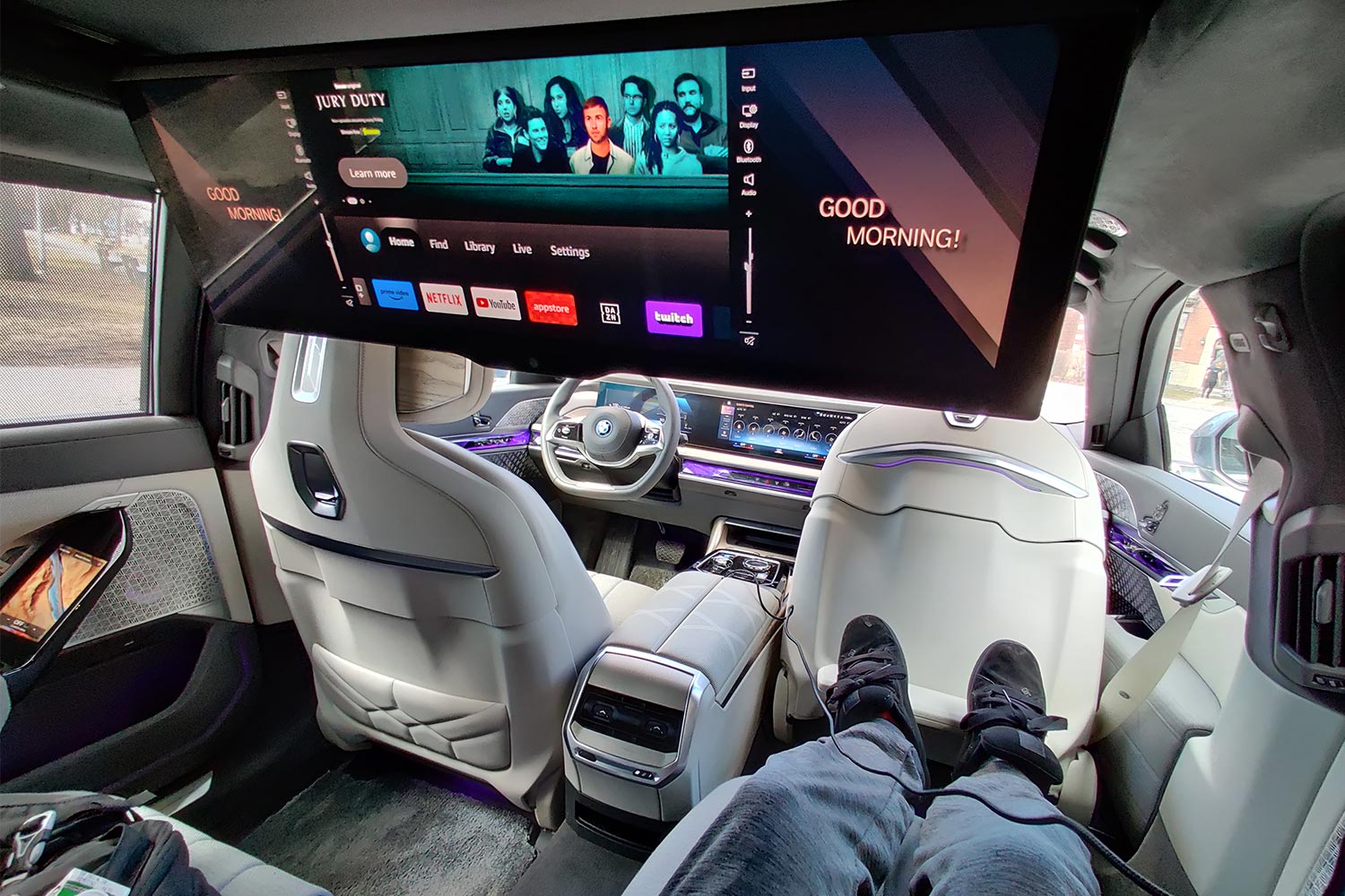Sitting in the backseat of a BMW i7 electric car watching TV on the 31.3-inch panoramic screen