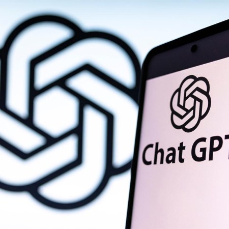 Photo illustration showing ChatGPT and OpenAI research laboratory logo and inscription at a mobile phone smartphone screen with a blurry background. The AI has been caught citing articles by The Guardian that don't exist.