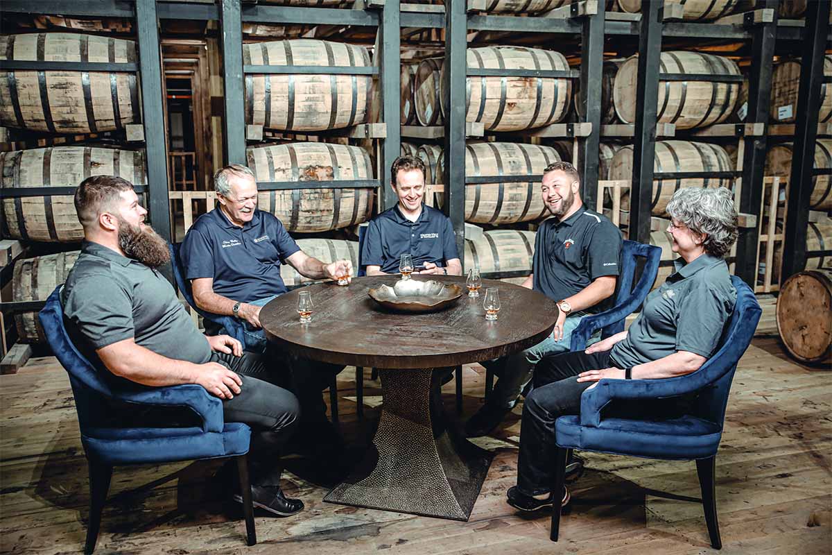 The distillers behind the Bardstown Collection in a rickhouse drinking whiskey