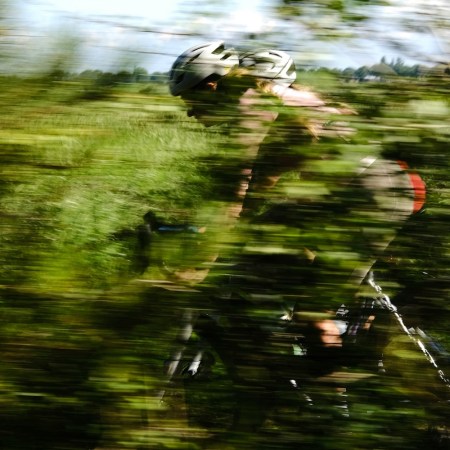 A blurry biker passing through a green field.