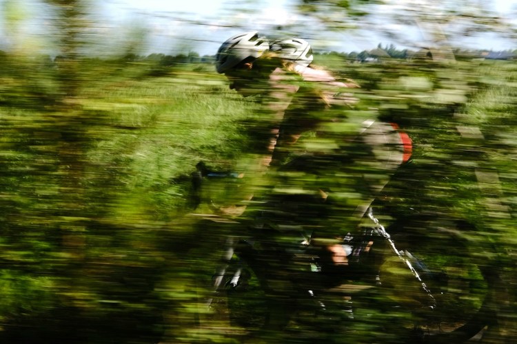 A blurry biker passing through a green field.