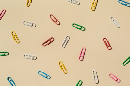 A bunch of paper clips scattered around a beige background. Here's how the habit-forming Paper Clip Strategy works.