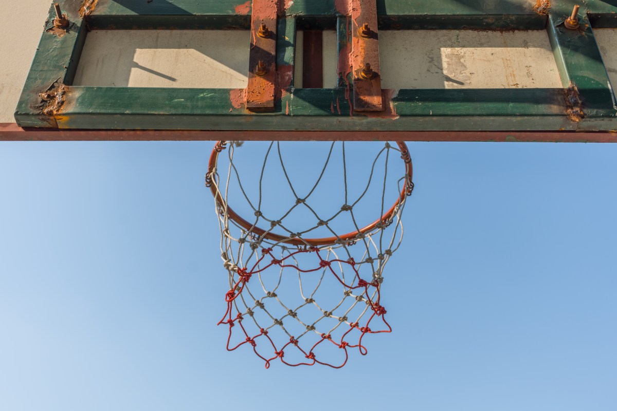 A view of a basketball net from below, blue sky above.
