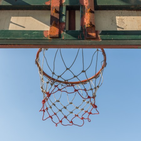 A view of a basketball net from below, blue sky above.