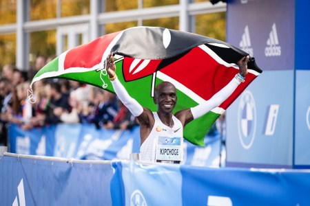 Eliud Kipchoge running with the Kenyan flag