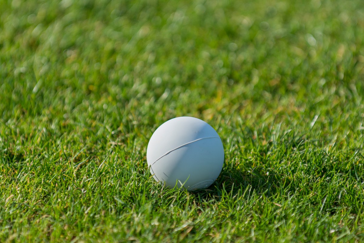 A lacrosse ball sitting on the grass. This $5 ball can be a great massage tool, better than a massage gun.