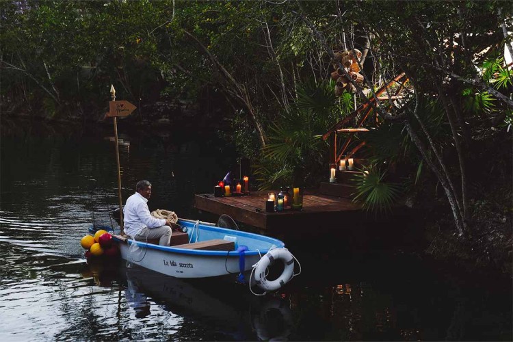 A man in a boat in front of La Isla Secreta, a speakeasy you can only reach by boat in Riviera Maya