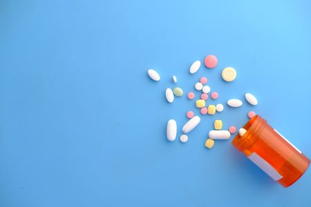 A bottle of pills spilling onto a counter. The FDA recently approved a second drug and the first pill made from human poop.