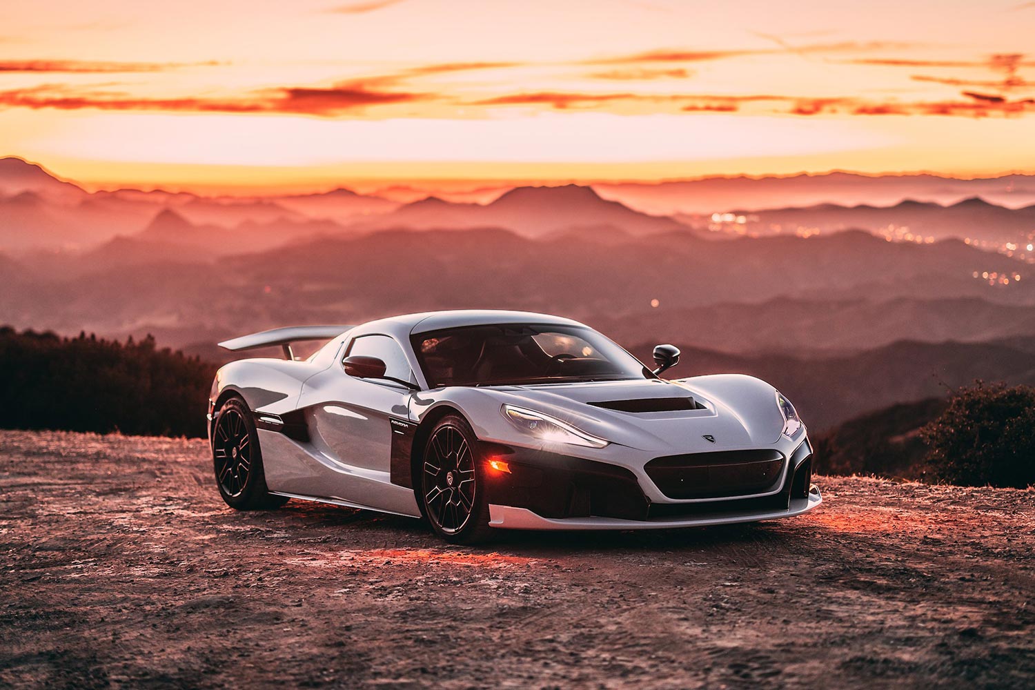 The Rimac Nevera electric supercar sitting on a cliff while the sun sets