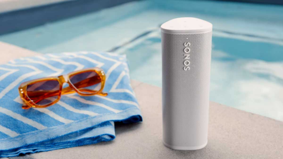 A Sonos Roam near a pool, towel and sunglasses. Sonos gear that is refurbished often nets you an extra discount.