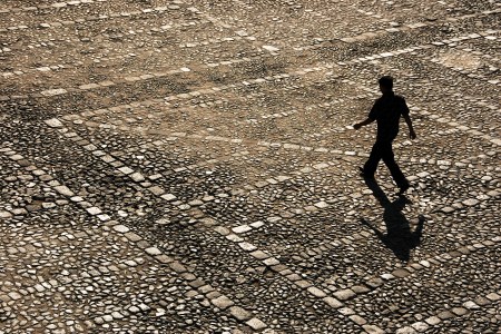 A man walking across cobblestones.