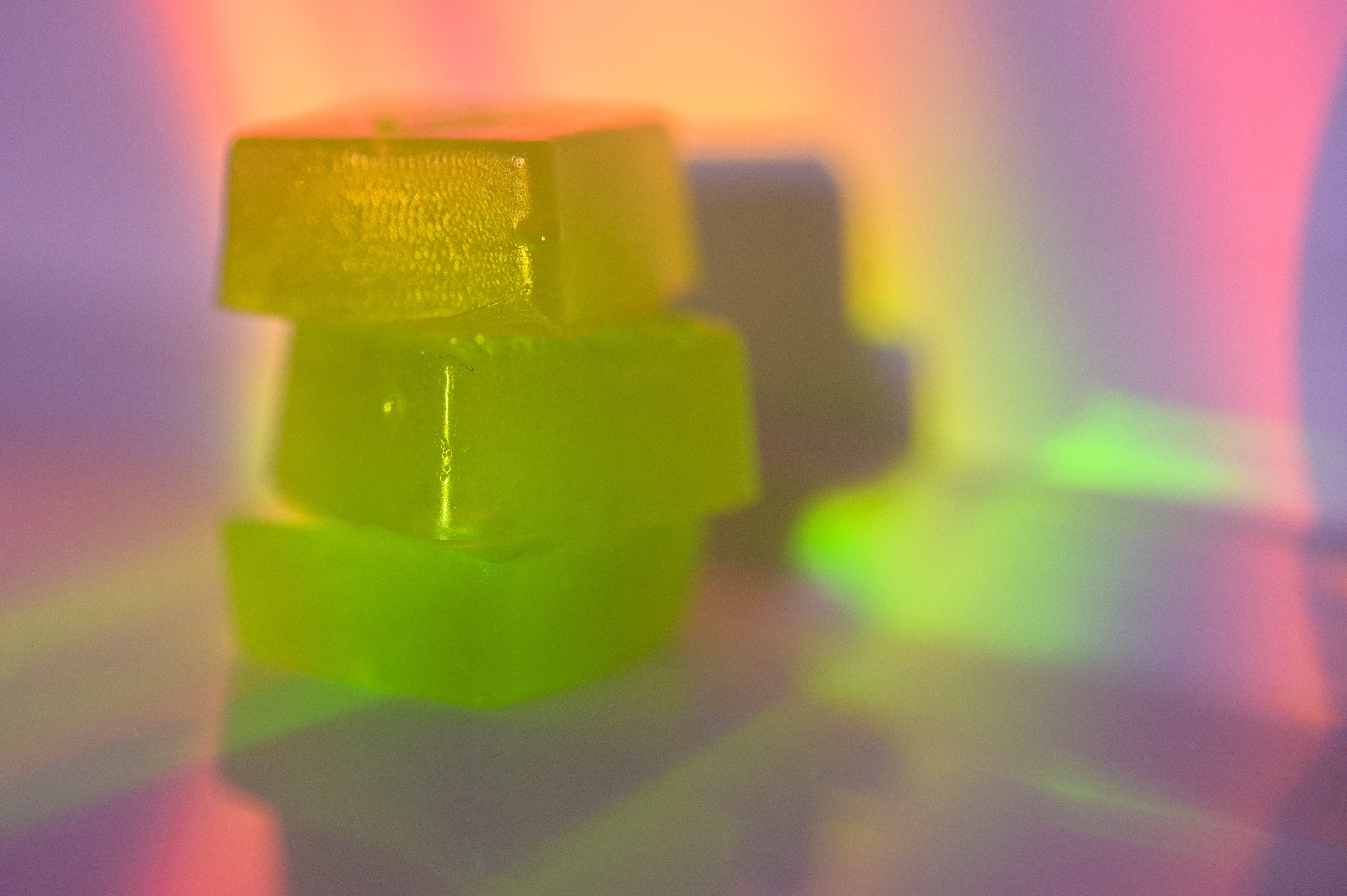 A stack of edible cannabis gummies in rainbow light