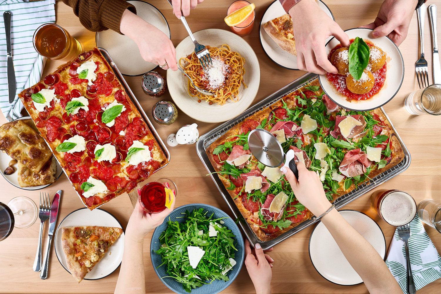 A table of food including pizzas and salad. 