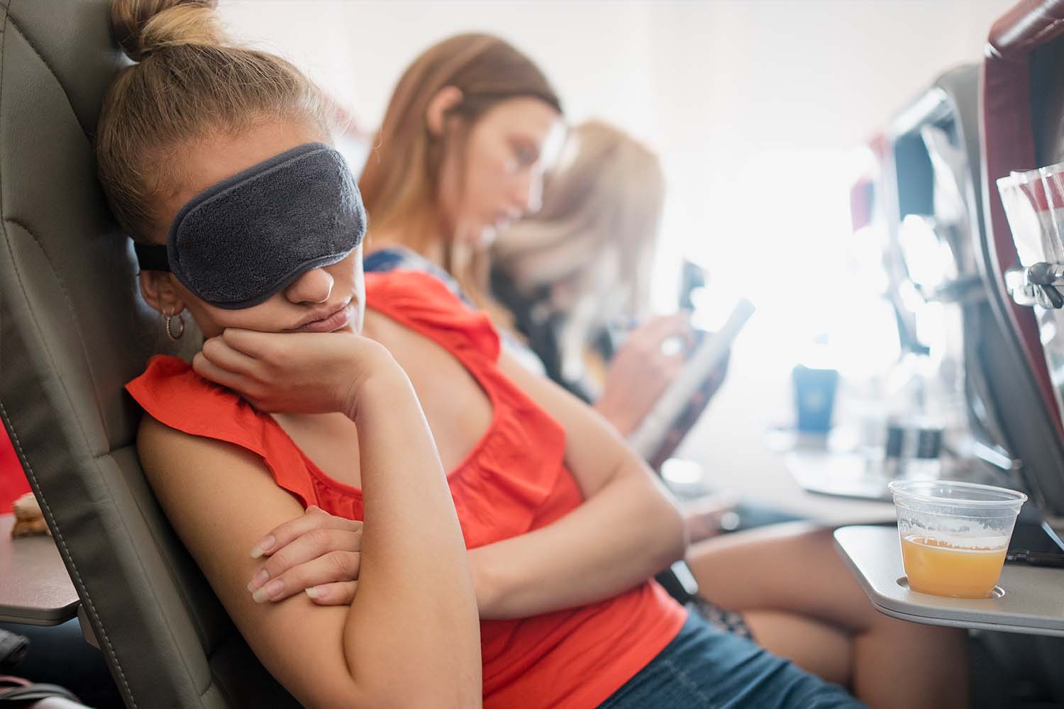 A young woman asleep on an airplane.