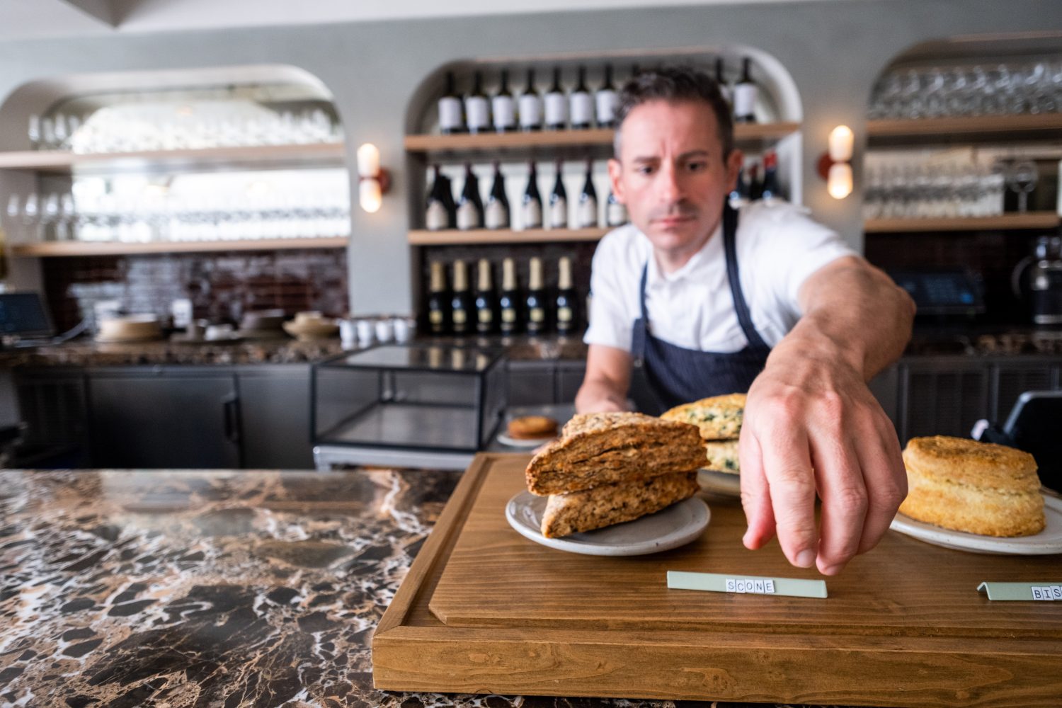 A chef hands a tray of food across the bar.