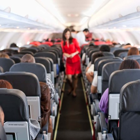 A flight attendant in the middle of an aisle on an airplane. Here's why flight attendants won't help you with your carry-on bags.