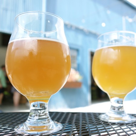 two wheat beer pints at a microbrewery in an outdoor courtyard table