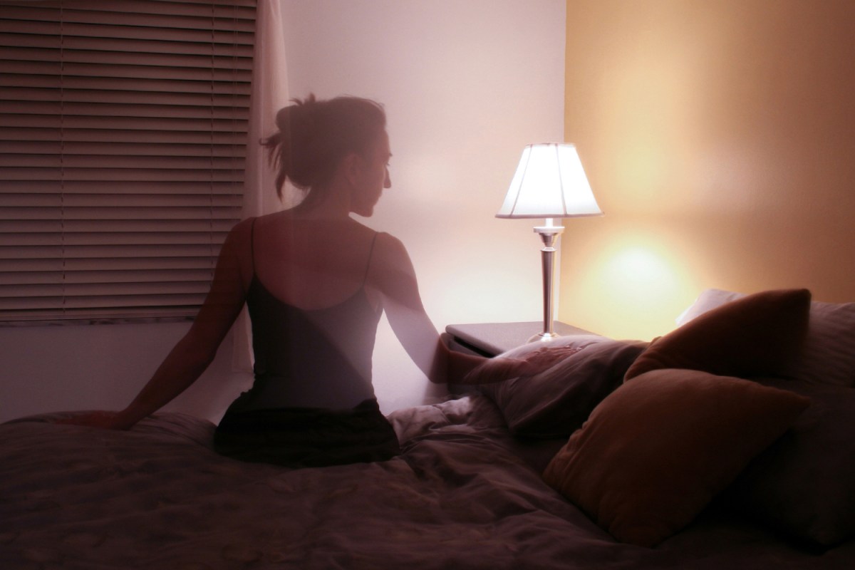 Silhouette of woman sitting on bed