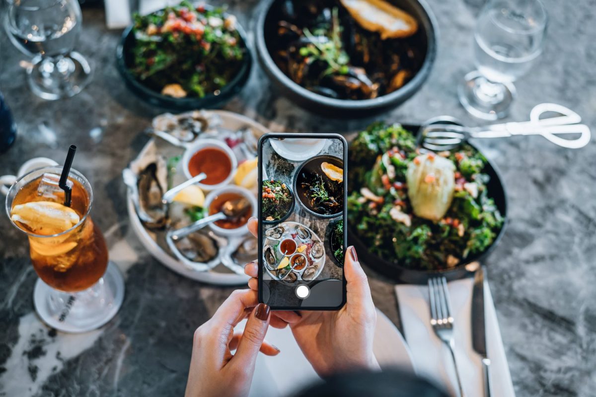 Overhead view of an influencer taking a photo of their food. Today, we look at the 10 food and drink Instagram accounts in Texas worth following.