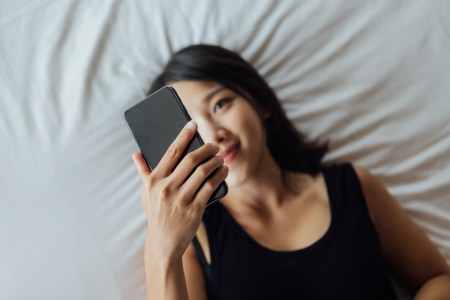 High angle view of young woman using smart phone on bed