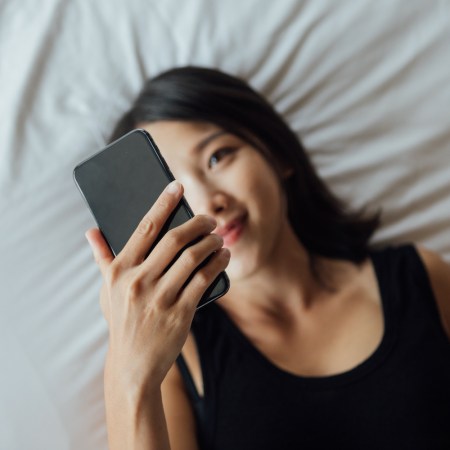 High angle view of young woman using smart phone on bed