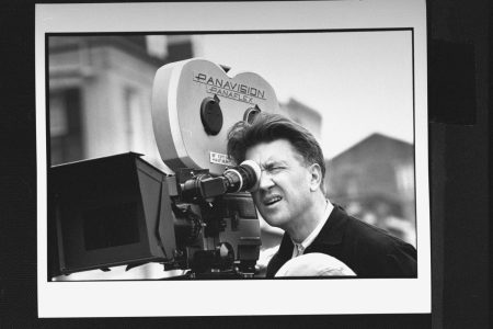 David Lynch looking into a film camera. Today, Daniel Knox ranks all of Lynch's films.