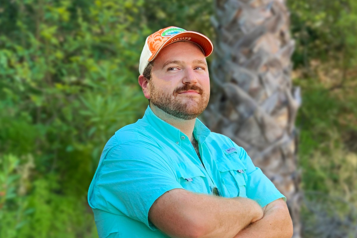 Johno Faherty, the creator of Survivor Drinking Game, stands with his arms crossed.