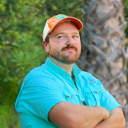 Johno Faherty, the creator of Survivor Drinking Game, stands with his arms crossed.