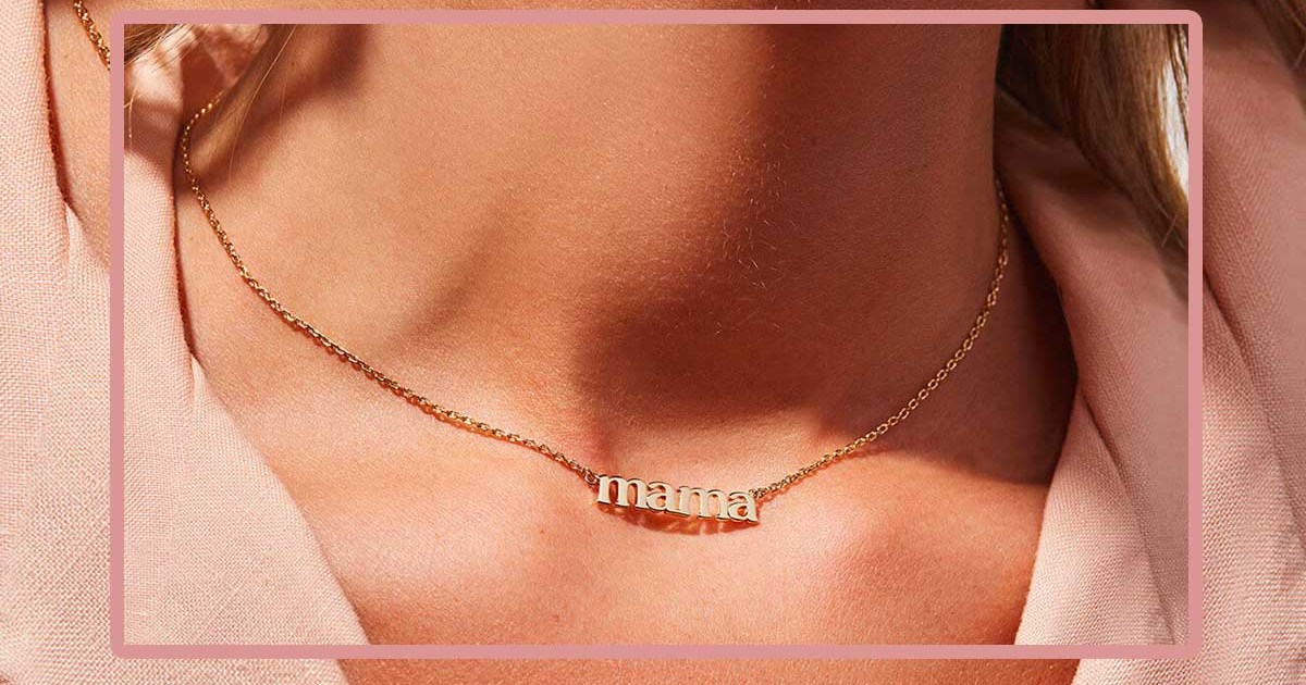 A woman wearing a necklace that spells "mama," a great piece o jewelry to gift this Mother's Day